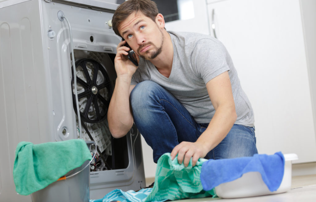 man phoning repair man to fix tumble dryer